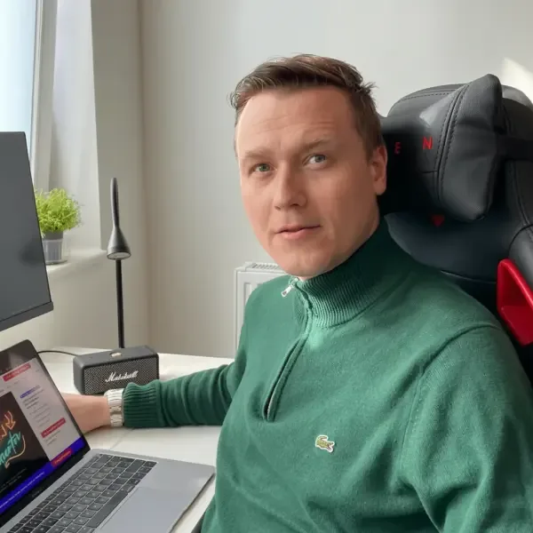 Przemek Milner am Schreibtisch, davor ein Monitor und ein Laptop mit geöffneter Website